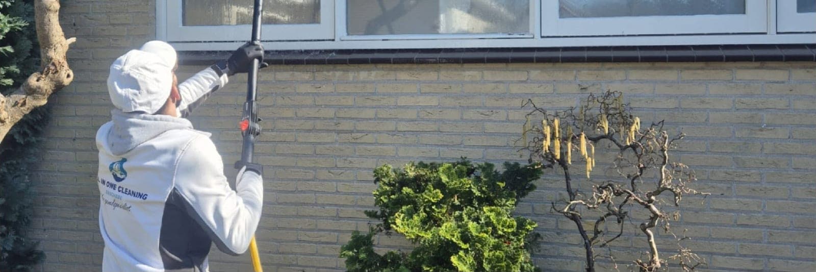 Na: medewerker van All in One Cleaning reinigt de gevel, de steen is weer licht